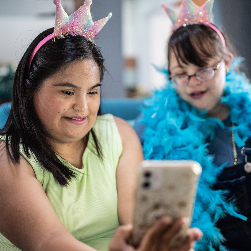 NDIS Provider Coomera participants enjoying a playful video call together during a social activity.