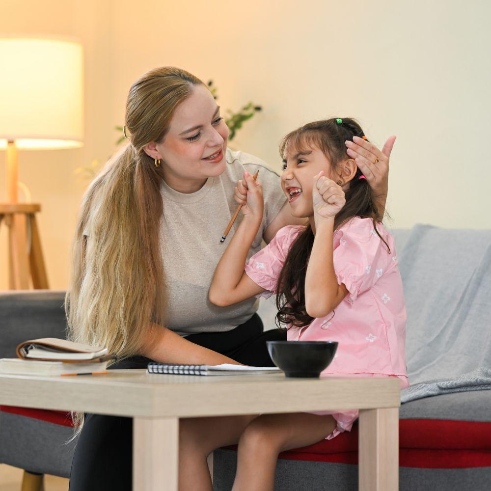 NDIS Provider Nerang support worker encouraging a young participant during a learning activity at home.