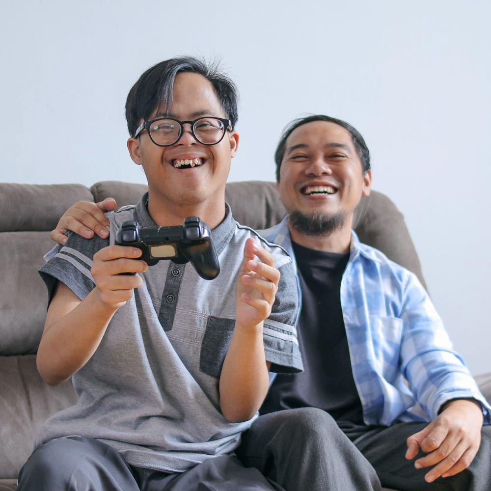 NDIS Provider Upper Coomera support worker enjoying a video game with a participant at home.